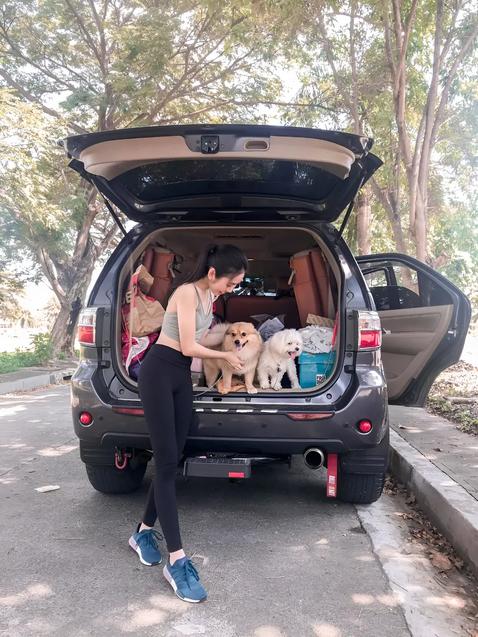 Stephanie Jean King with two dogs in open car trunk outdoors