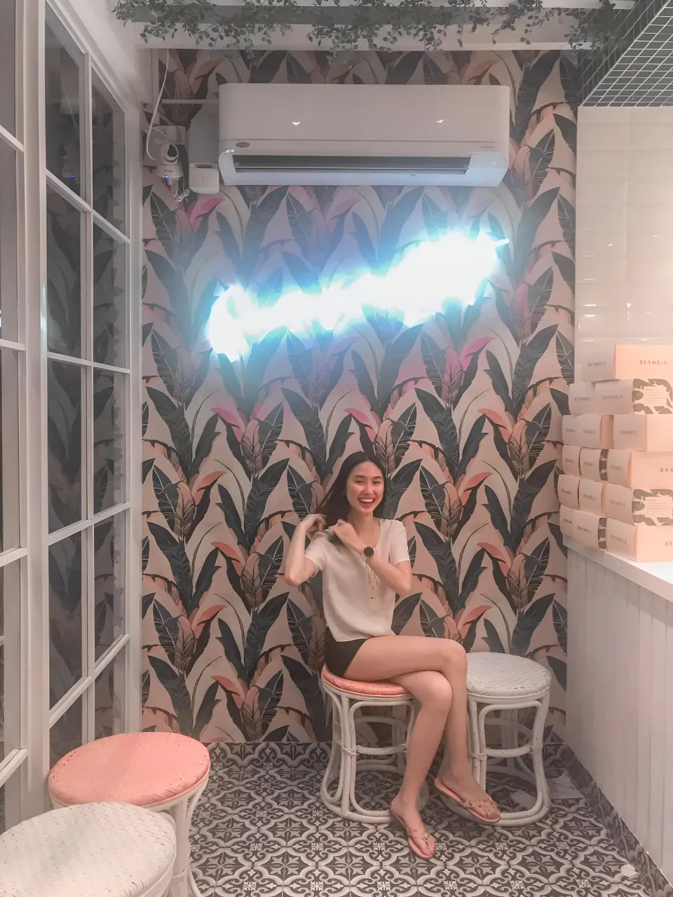 Stephanie Jean King sitting on stool in patterned room with tropical wallpaper