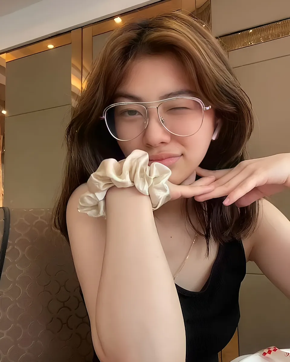 Thea Herrera wearing glasses and scrunchie, seated indoors