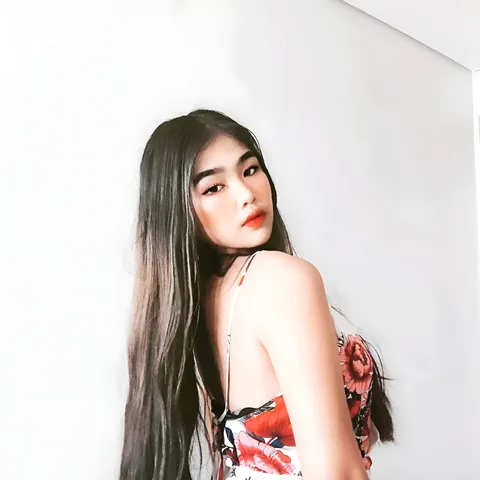 Trisha Shima Herance in floral top poses against plain white wall