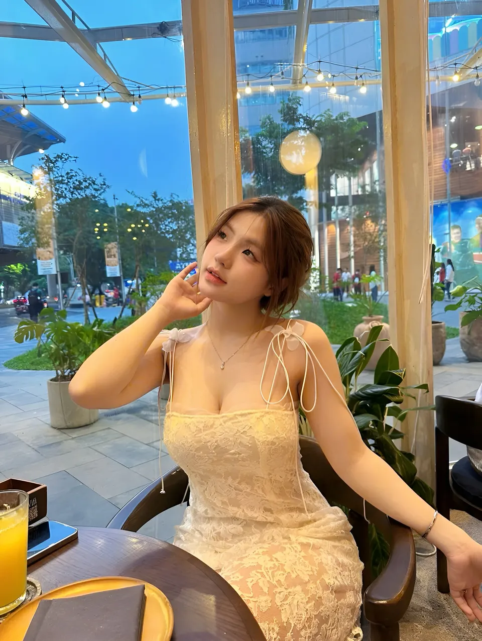 Yue Arden in lace dress seated at table in glass-walled cafe