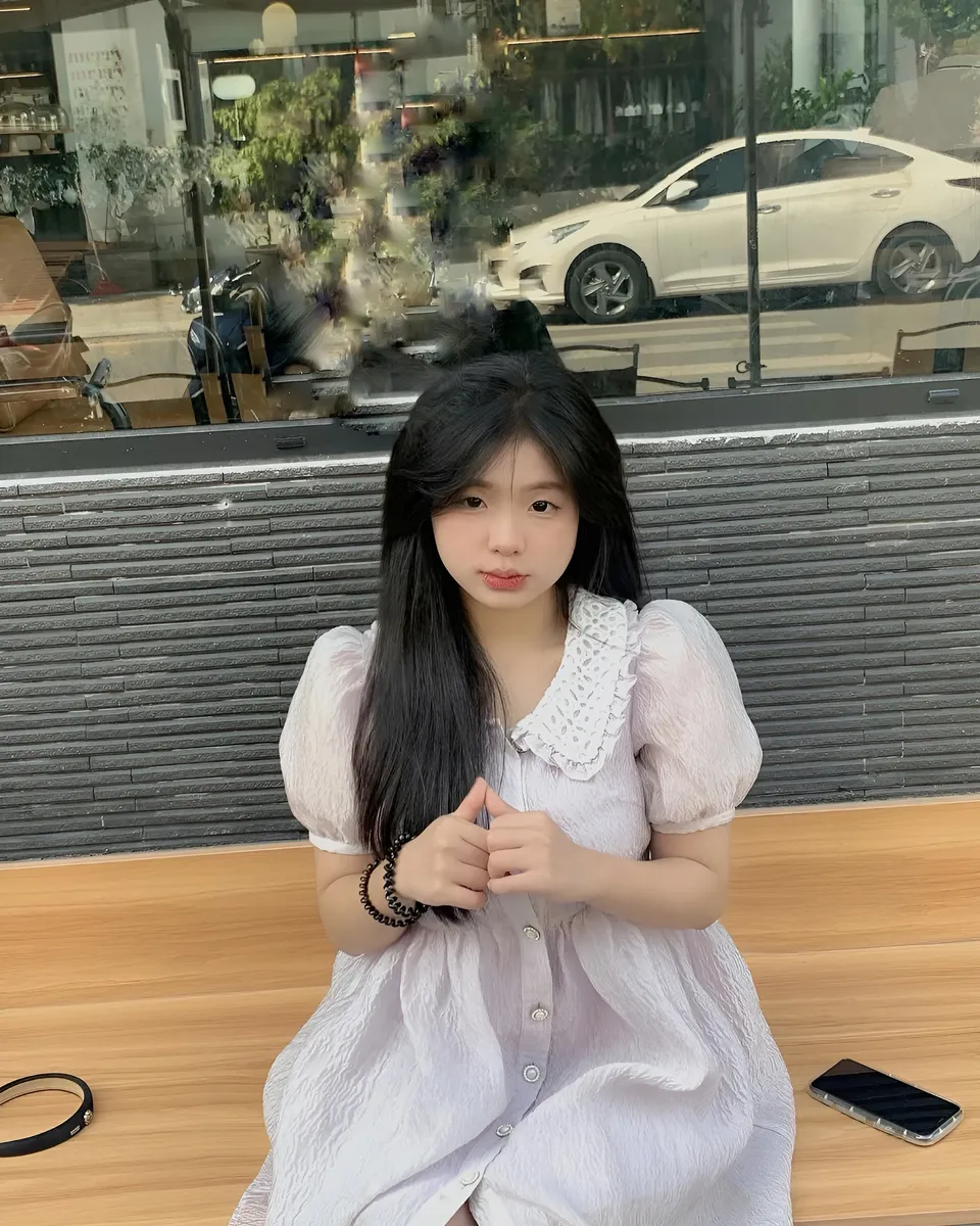 Yue Arden in light dress seated at wooden table outdoors