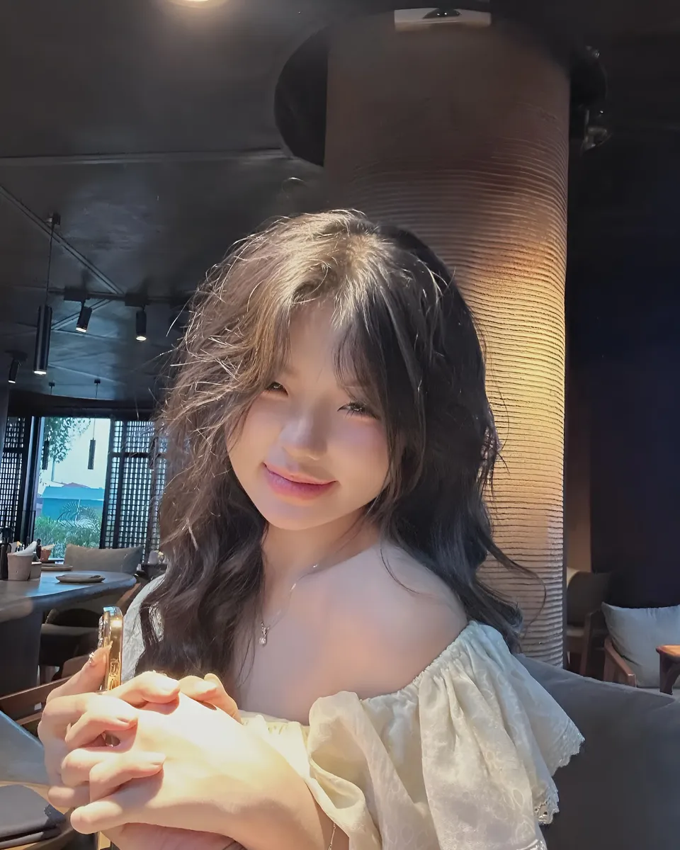Yue Arden in off-shoulder top seated indoors near pillar
