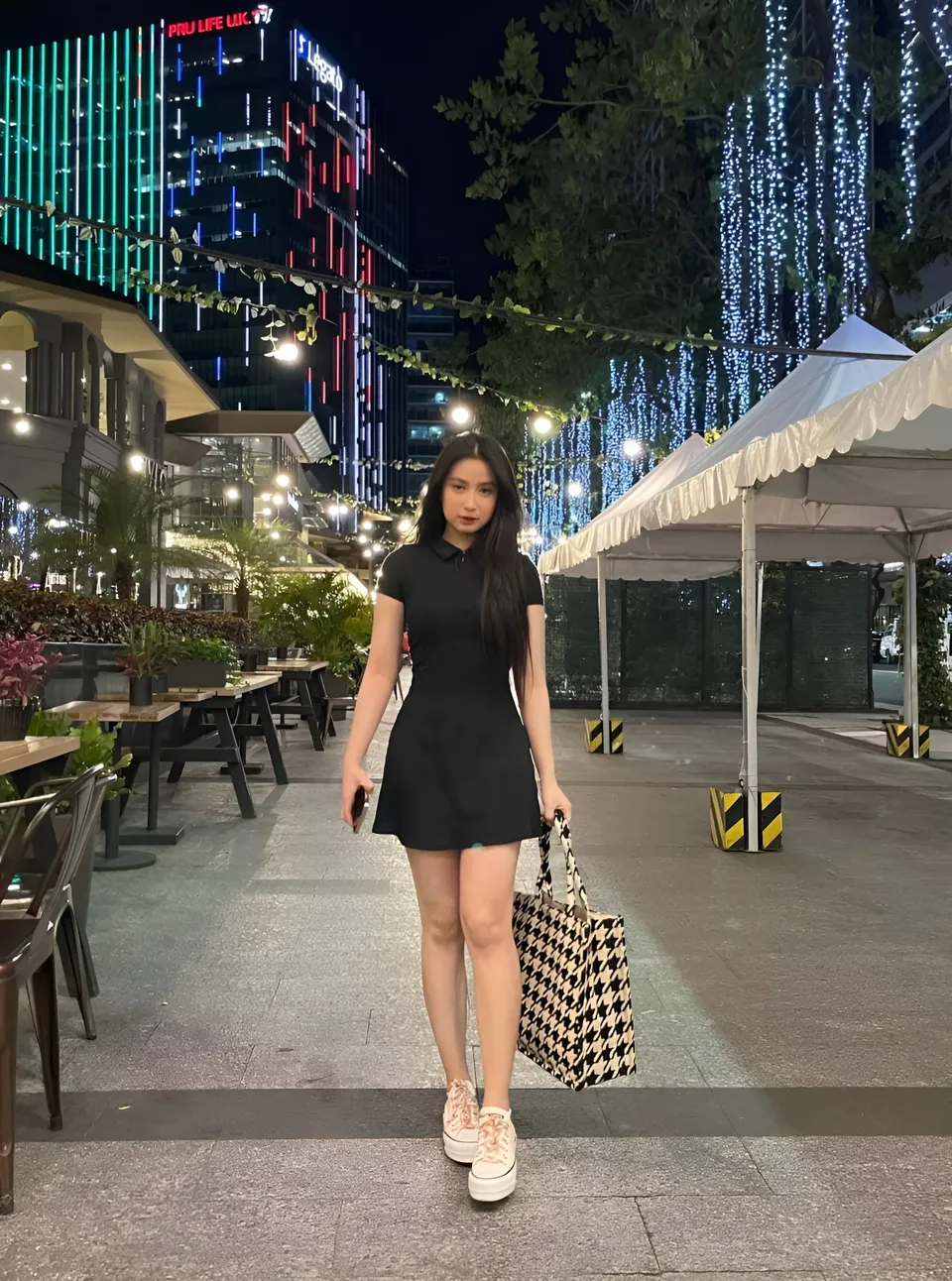 Yumi Garcia in black dress standing on paved walkway at night