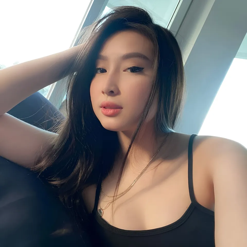 Yumi Garcia in black top with hand behind head near window