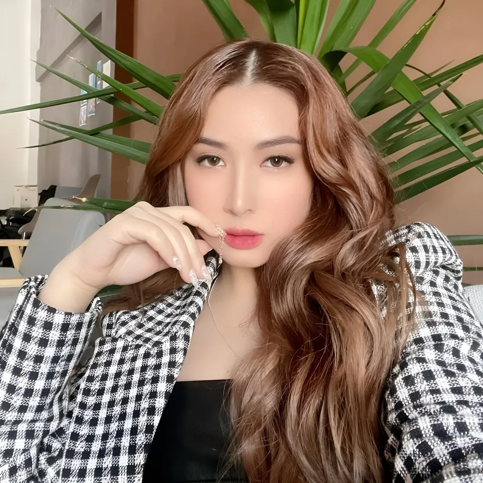 Yumi Garcia in checkered jacket with hand near face