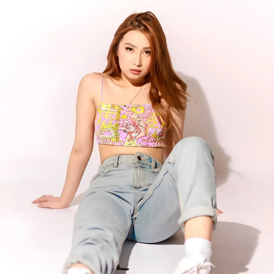 Yumi Garcia wearing colorful top and jeans sitting on floor