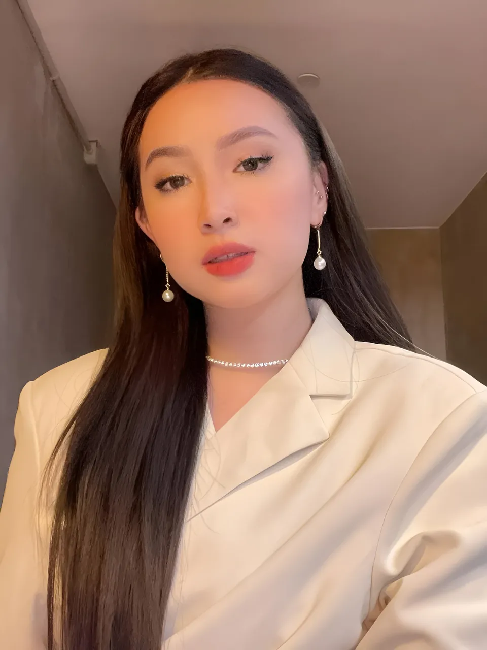 Yumi Garcia in white blazer with pearl earrings and choker