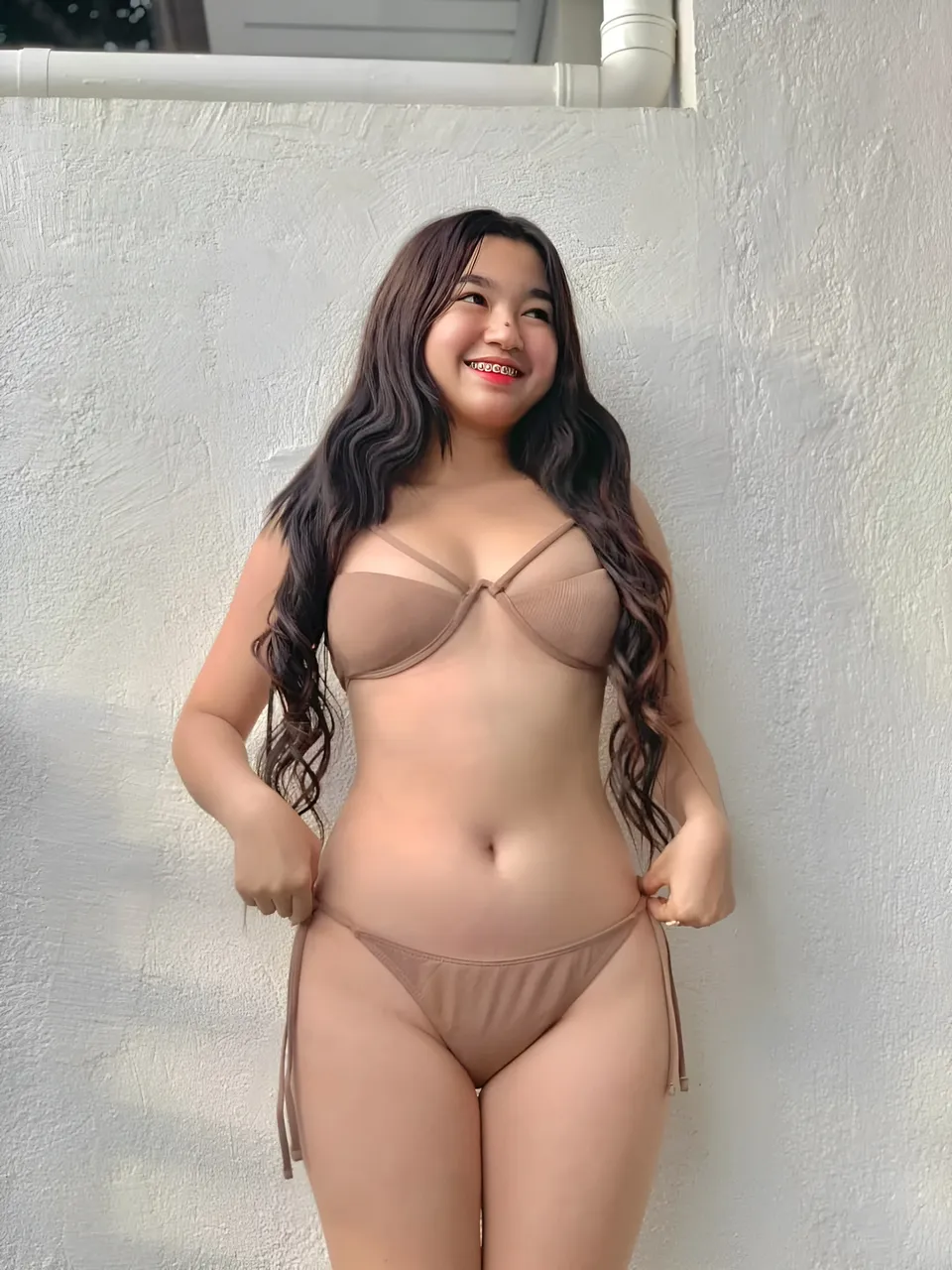 Yumi Mizayaki in beige bikini standing against textured white wall