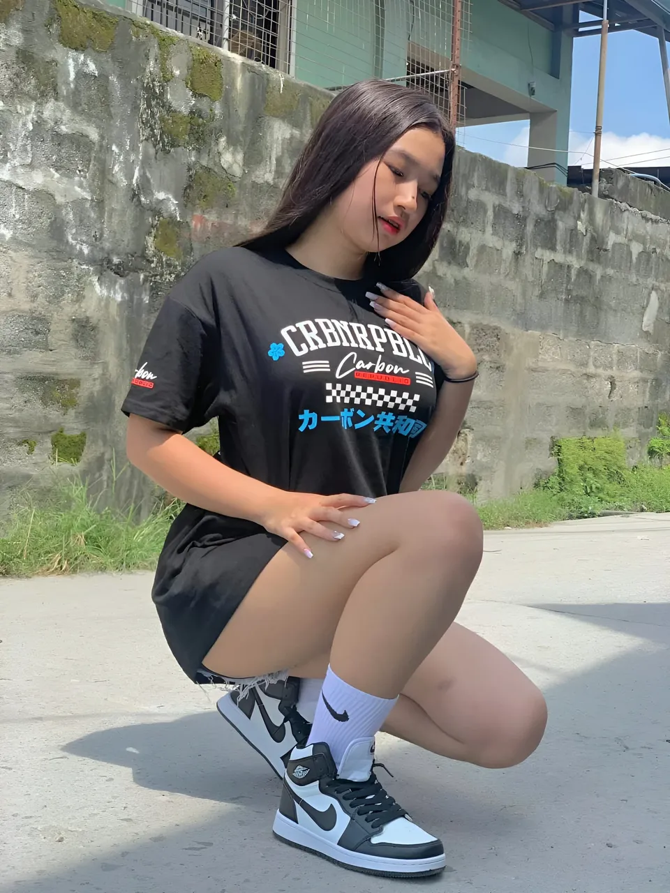 Yumi Mizayaki crouching in black t-shirt and sneakers outdoors
