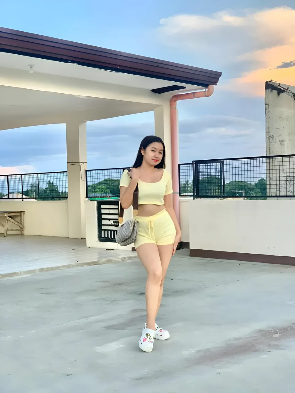 Yumi Mizayaki in yellow outfit standing on rooftop with sky background