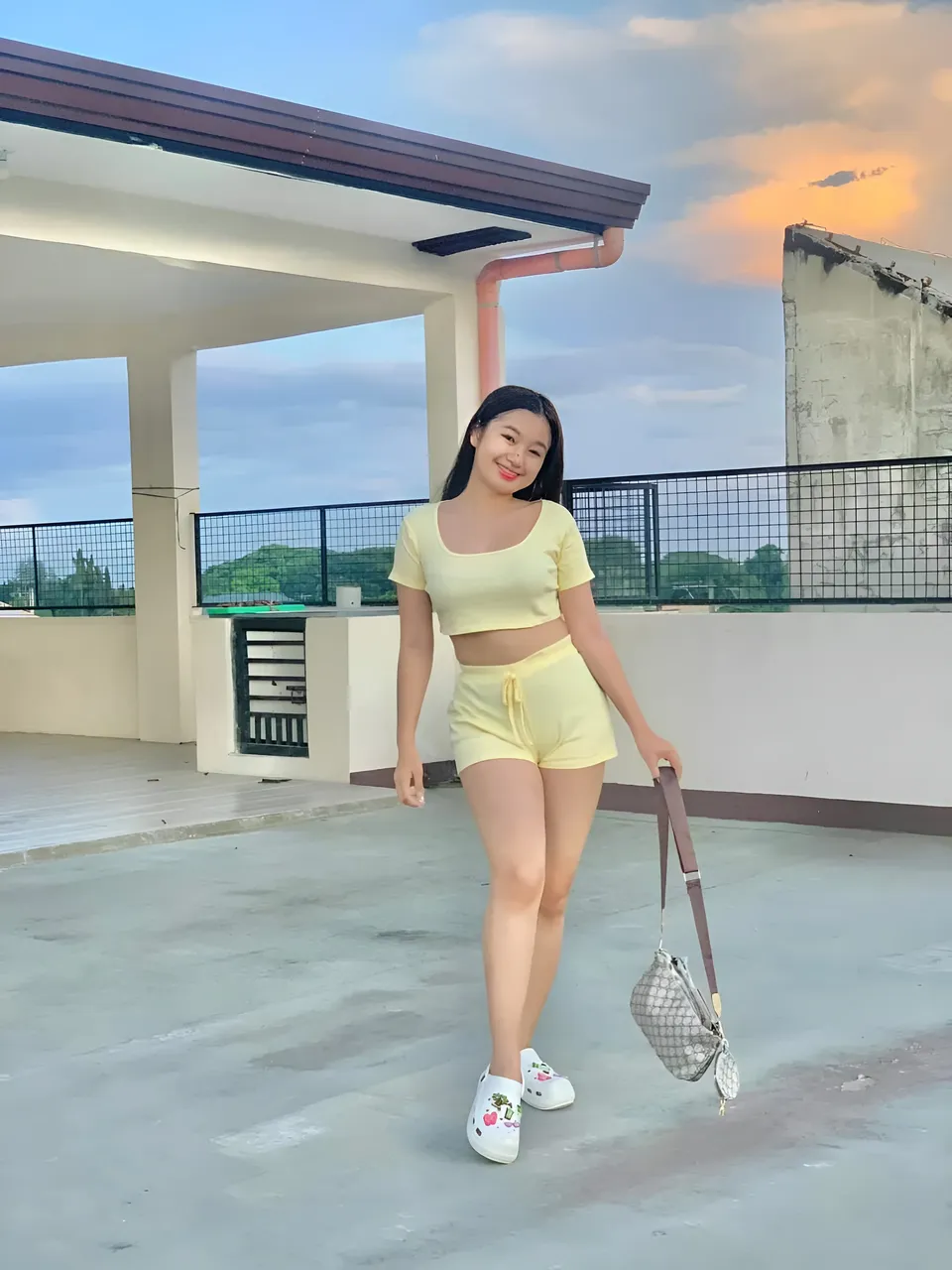 Yumi Mizayaki in yellow top and shorts standing on rooftop