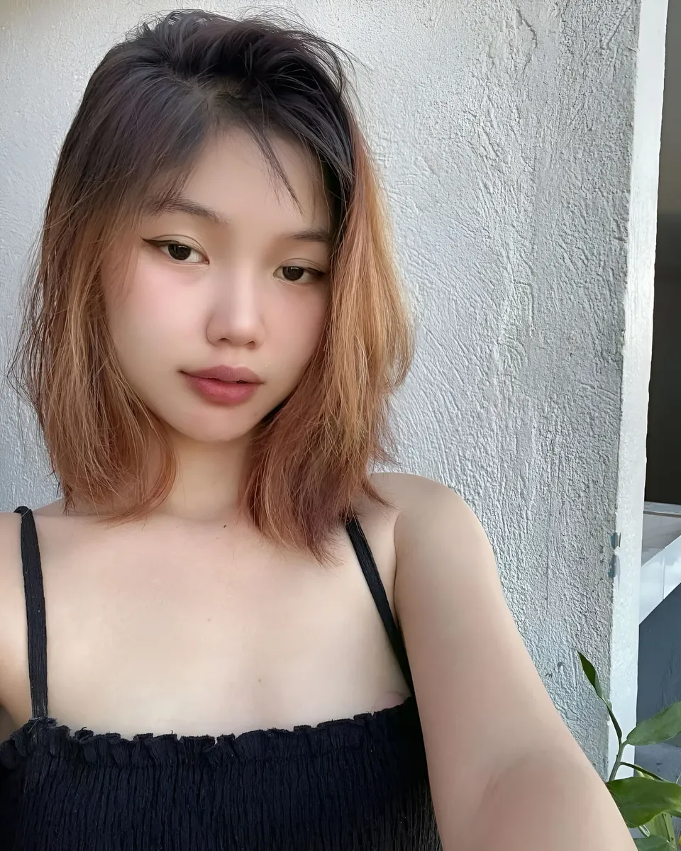 Zandra Hayes in black top with shoulder straps, standing against textured wall