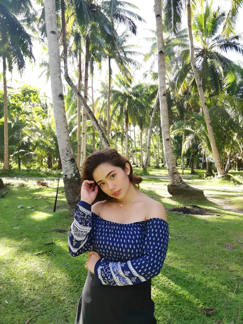 Zianne Tremedal in blue patterned top posing outdoors among palm trees