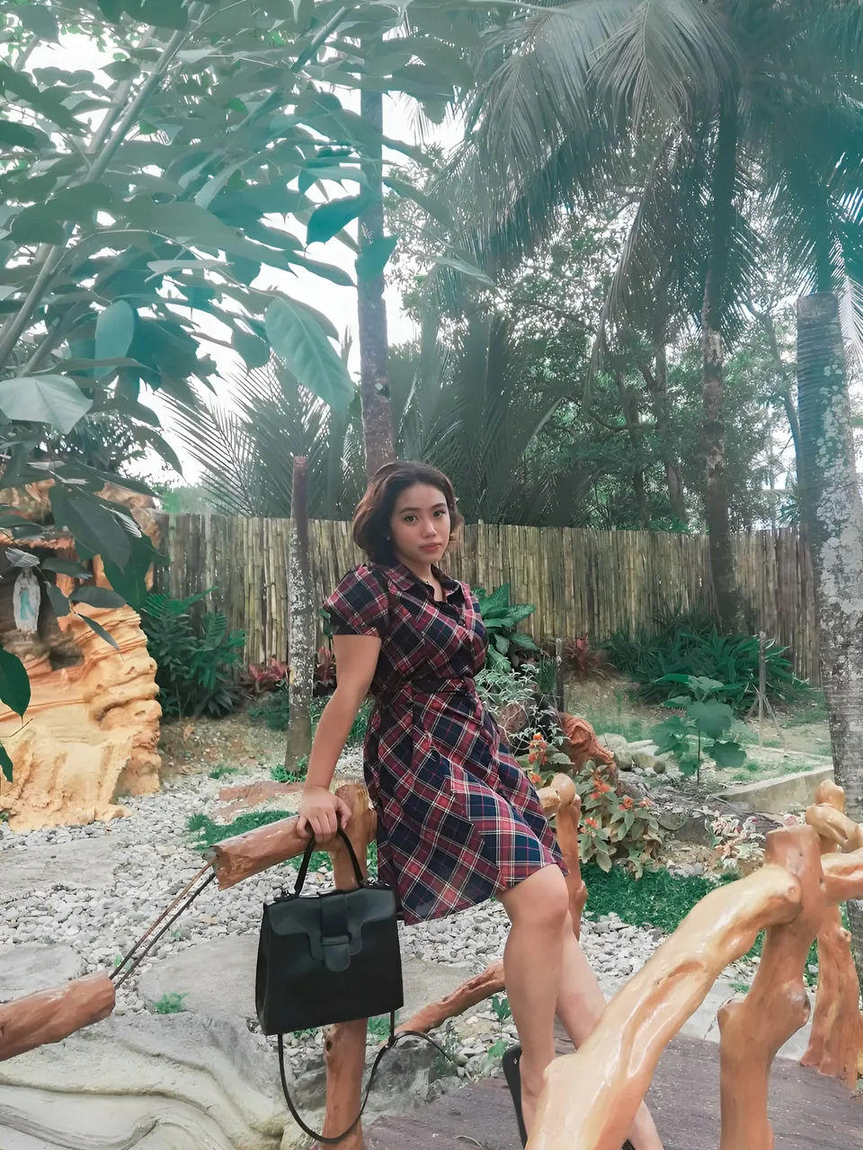 Zianne Tremedal in plaid dress standing on wooden structure outdoors