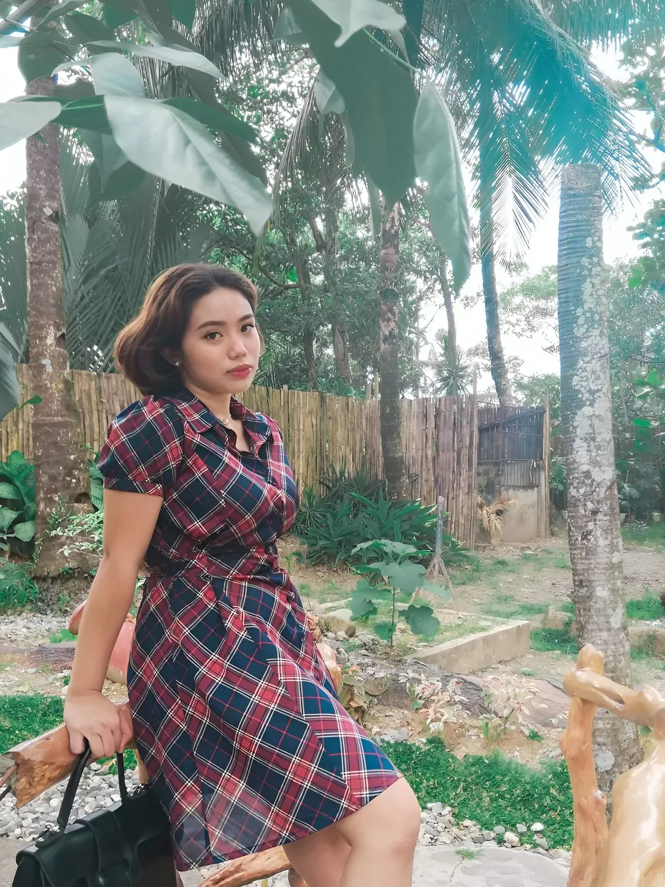 Zianne Tremedal in red and blue plaid dress standing outdoors under trees