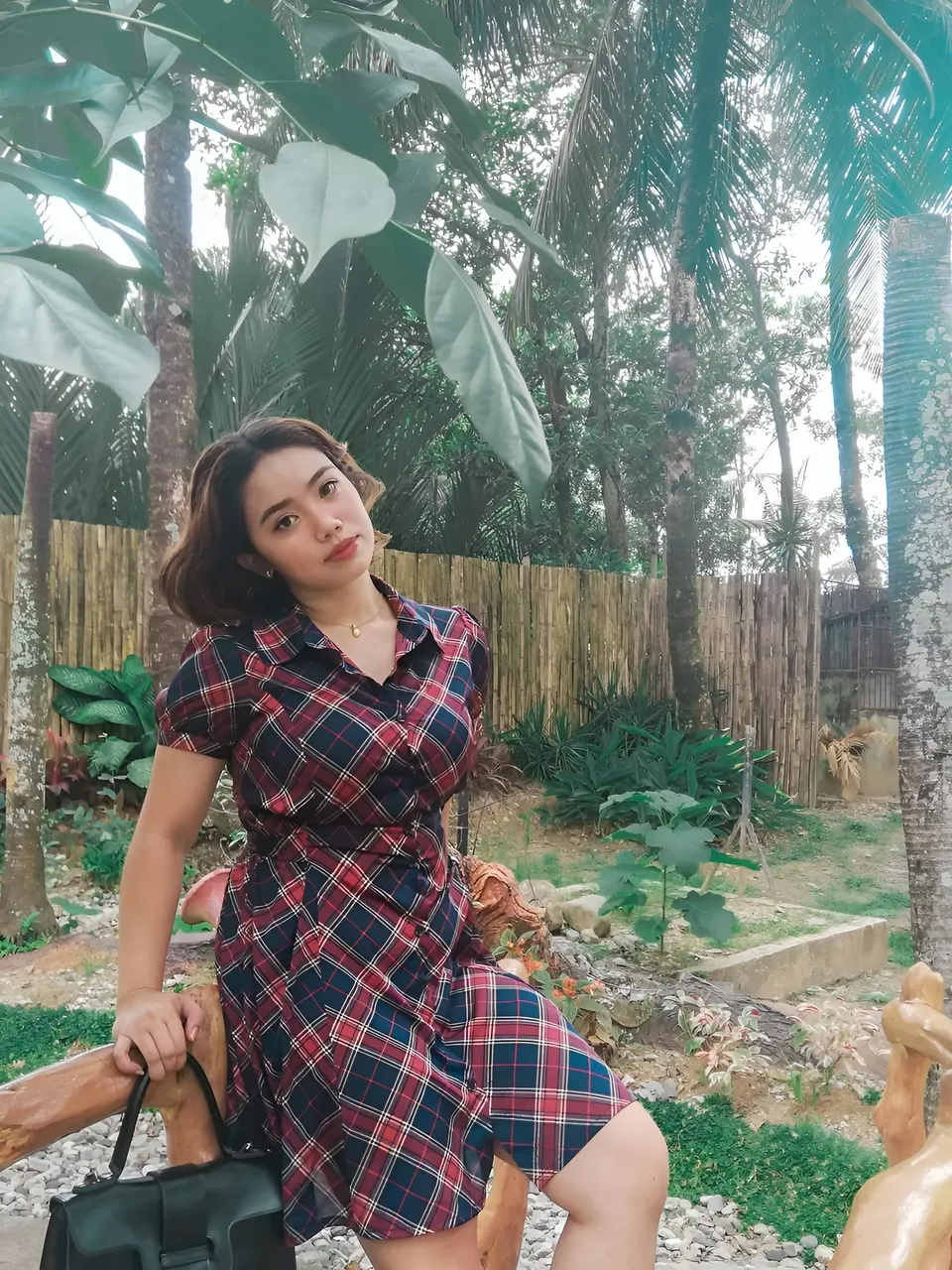 Zianne Tremedal wearing a red and navy plaid dress poses among trees
