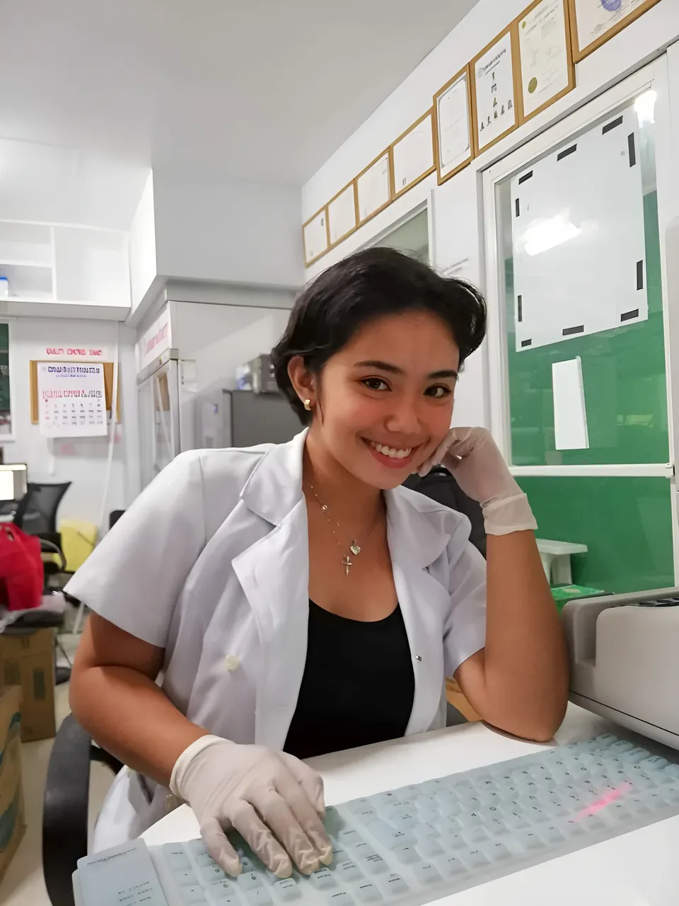 Zianne Tremedal in white coat typing at desk with gloves on