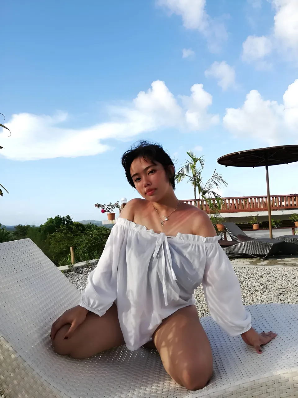 Zianne Tremedal in white off-shoulder top seated on lounge chair outdoors