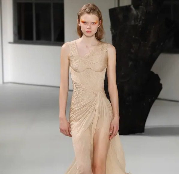 Model presenting a neutral-toned dress on the runway